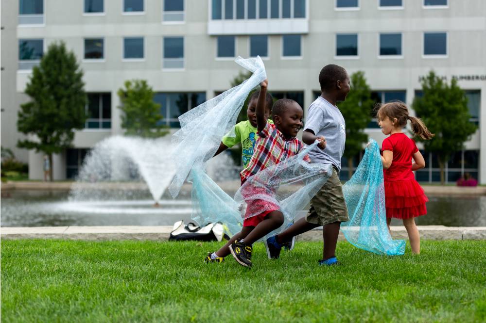 Four kids running with water-like fabric